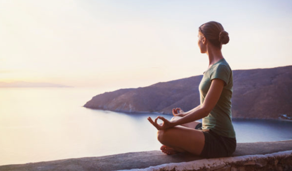 Woman in half lotus pose looks out into the distance, for an article on the future of yoga.